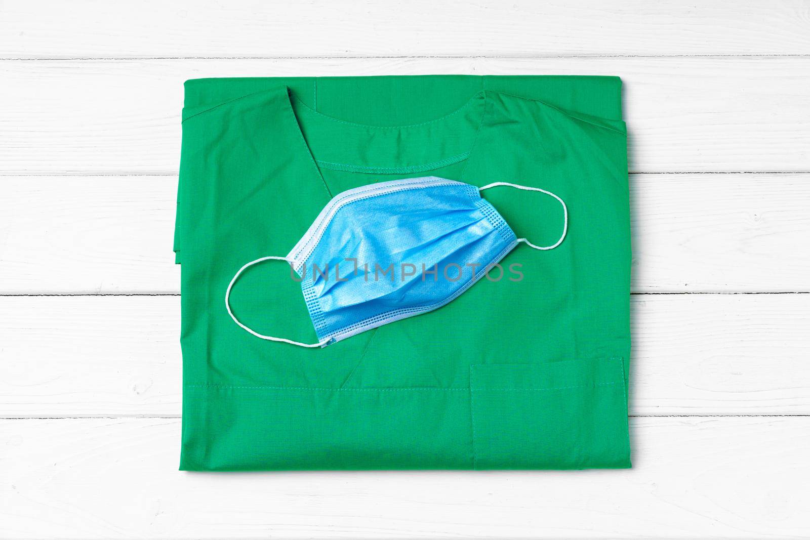 Doctor uniform with medical face mask close up on wooden desk