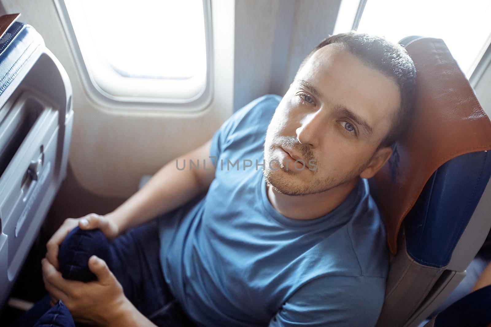 Male passenger feeling dizzy having airsickness while traveling on plane. Man looking at camera