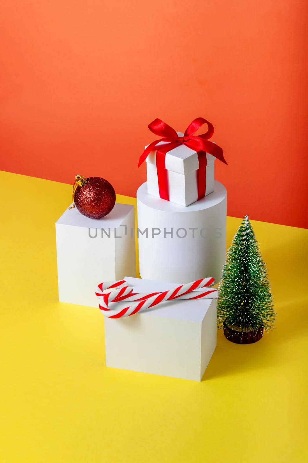 Creative Minimal Christmas Concept with Fir Tree, Gift Box, Ball and Candys on Different Geometrics Podium.