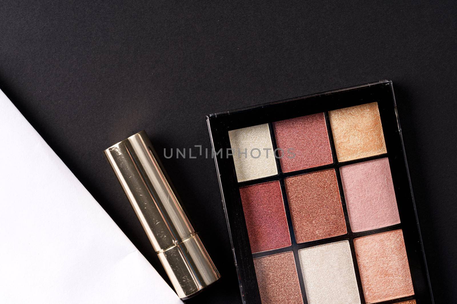 various makeup products on black texture background. close up