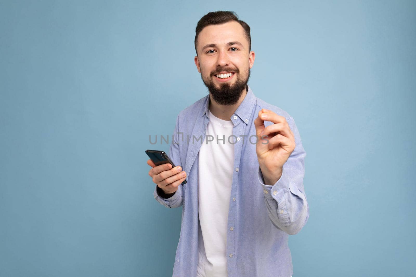 a young man with a beard on the background of a blue wall shows a gesture delicious.