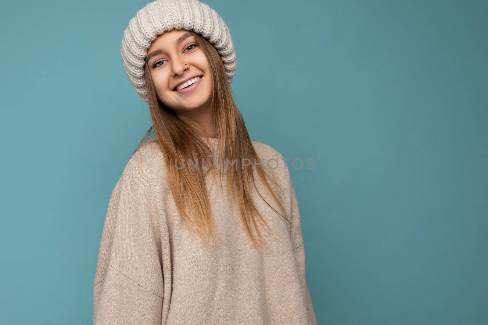 Attractive smiling happy young dark blond woman standing isolated over colorful background wall wearing everyday stylish outfit showing facial emotions looking at camera. Empty space