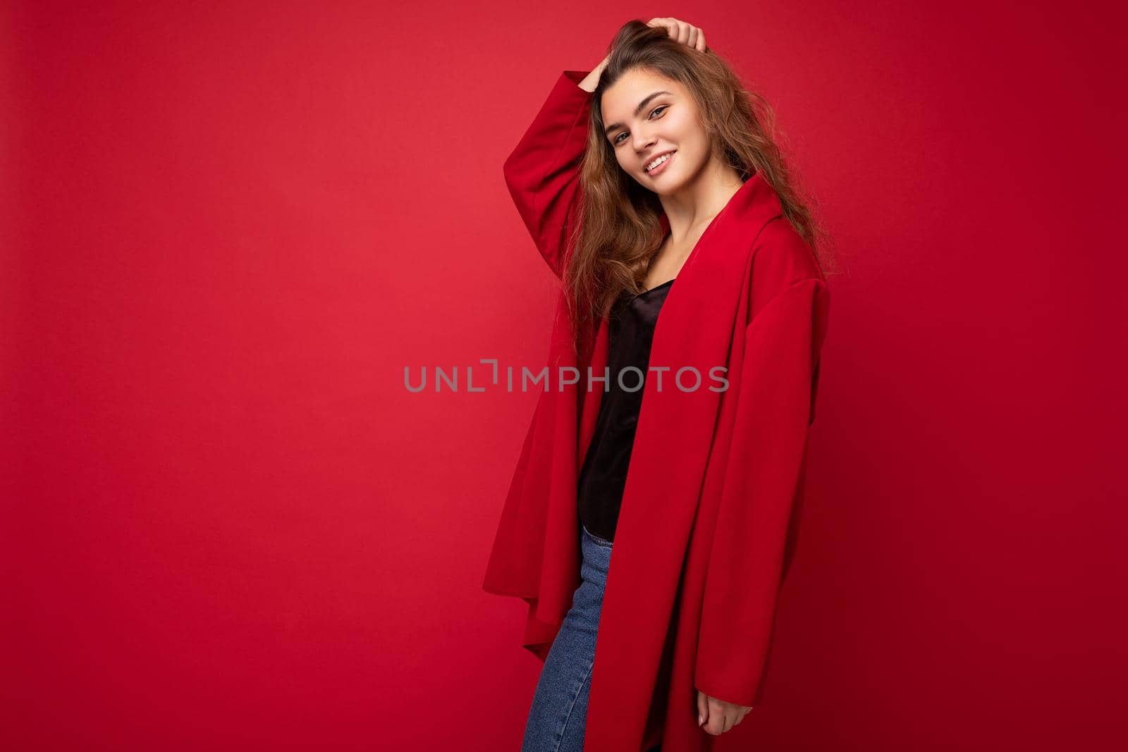 Young beautiful european stylish brunette woman wearing red cardigan isolated over red background with positive sincere emotions. Simple and natural looking at the camera. Free space by TRMK