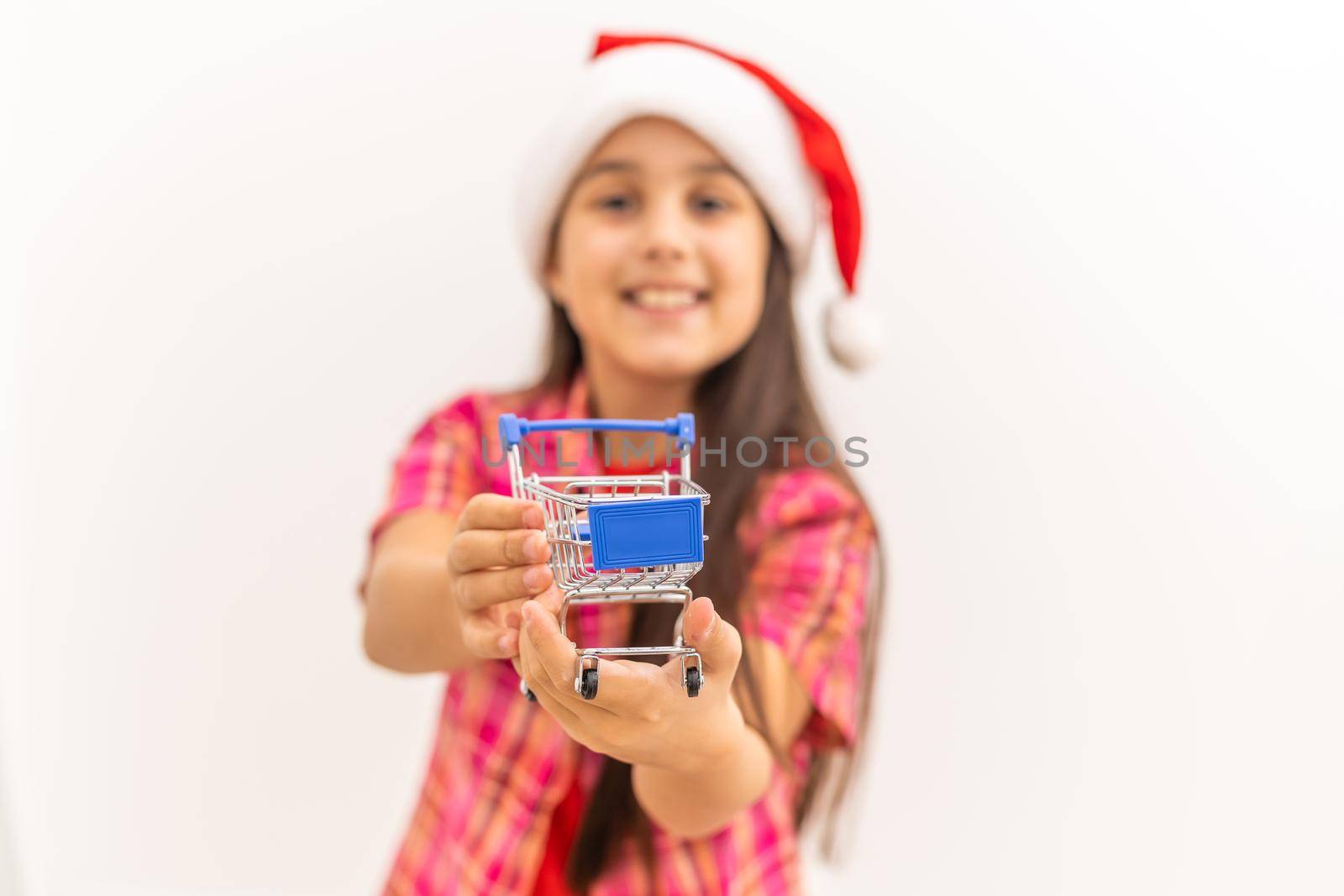 shot of a little girl pushing presents in a mini shopping cart isolated on white background.