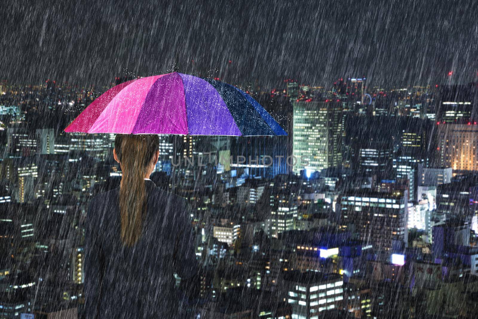business woman holding multicolored umbrella with falling rain at tokyo city background, Japan