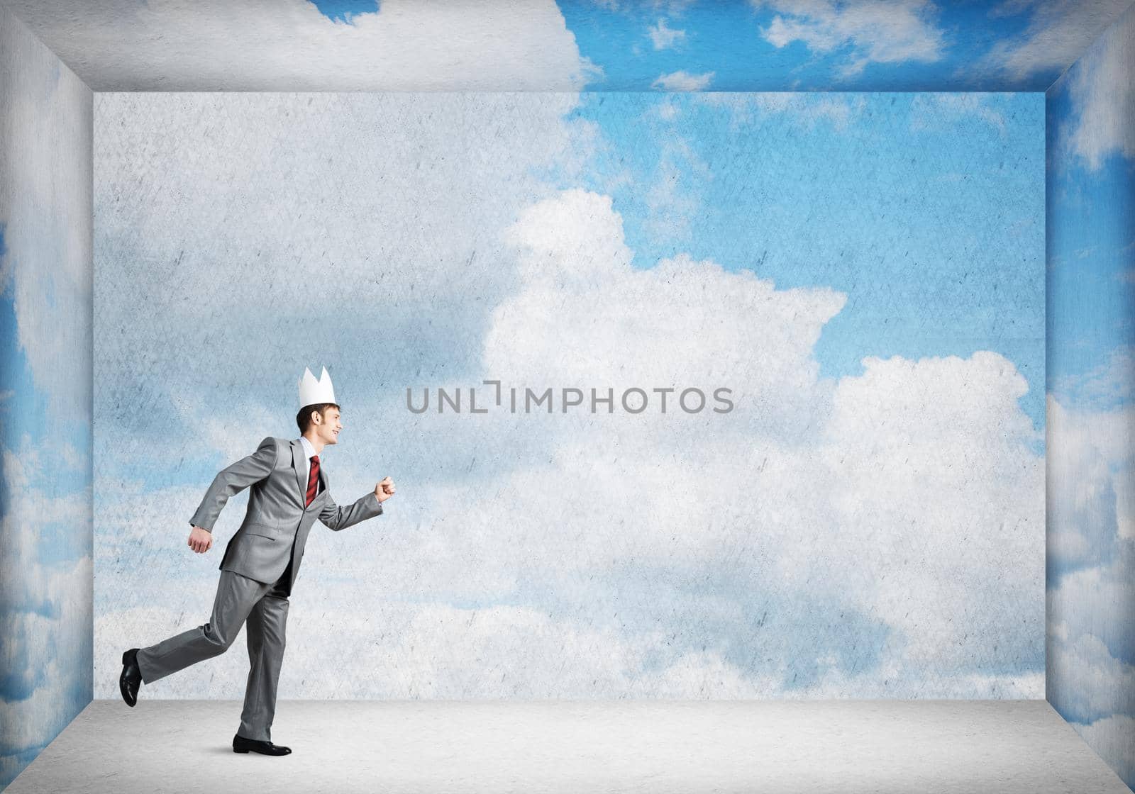Young handsome businessman wearing white paper crown running in a hurry