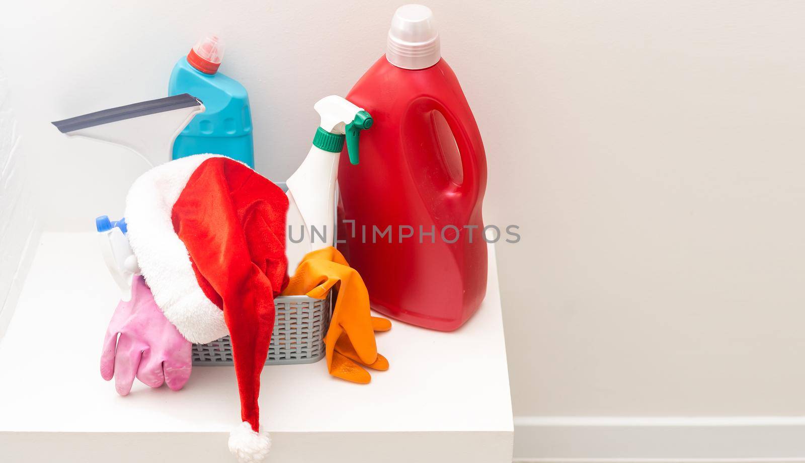 Christmas cleaning. Christmas shopping. Cleaning tools and Christmas decorations in santa hat home background with copy space.
