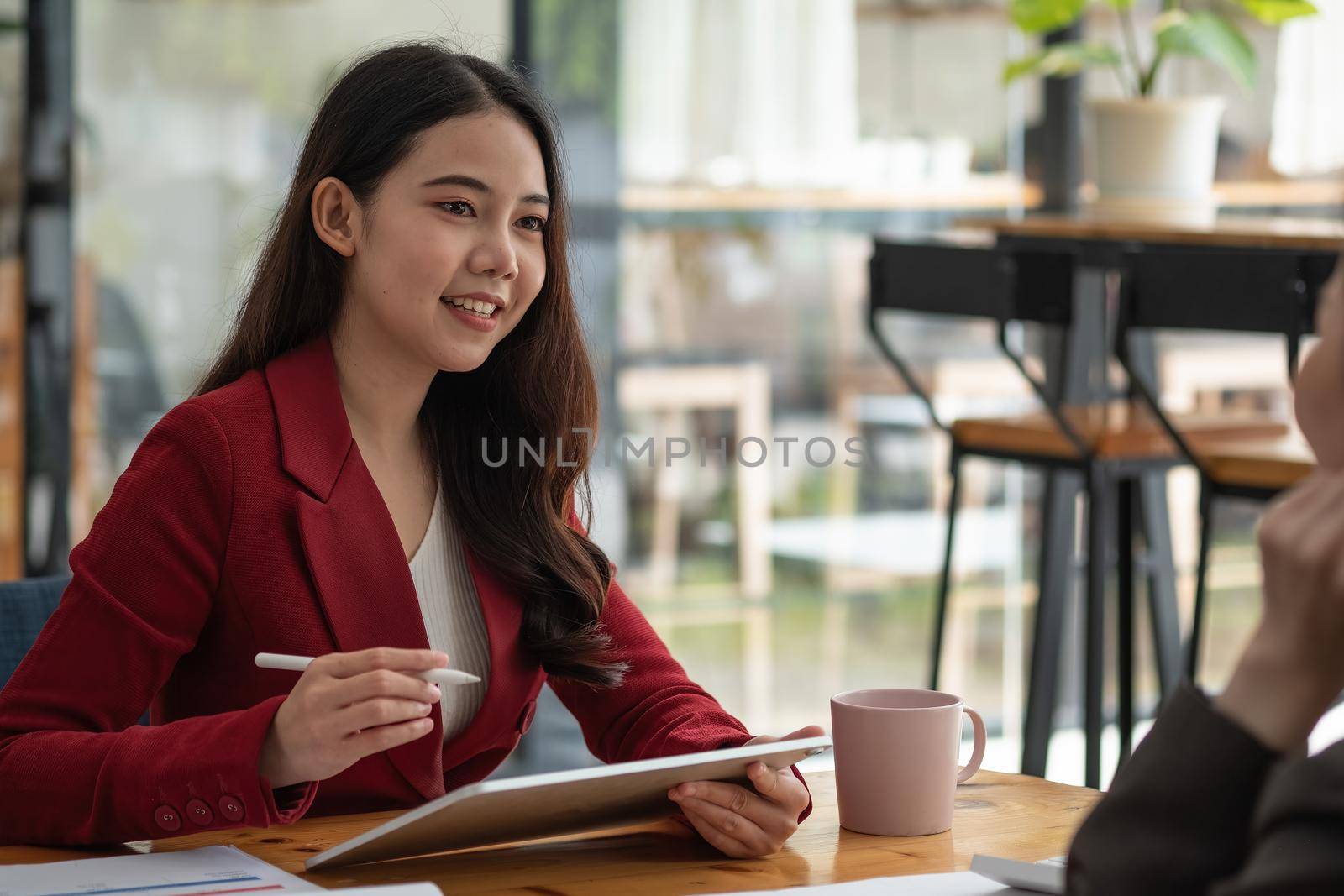 Young business woman holding a pen pointing the graph and partnership to analyze the marketing plan with calculator on wood desk in office.