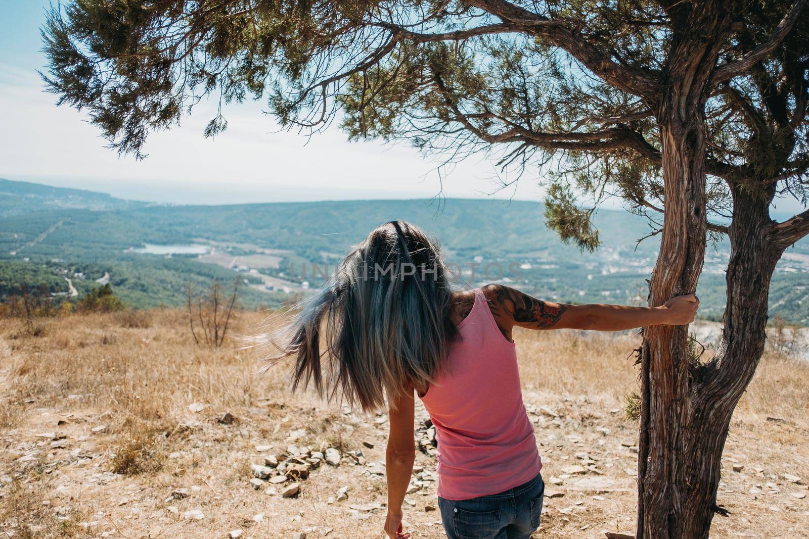Young woman looking at town in the mountains in summer, rear view