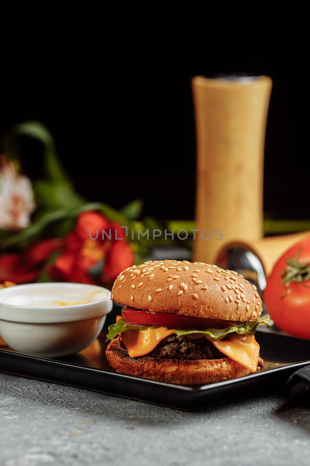 Concept: restaurant menus, healthy eating, homemade, gourmands, gluttony. Trendy burger with chicken in black bun with ingredients and french fries on messy vintage wooden background.