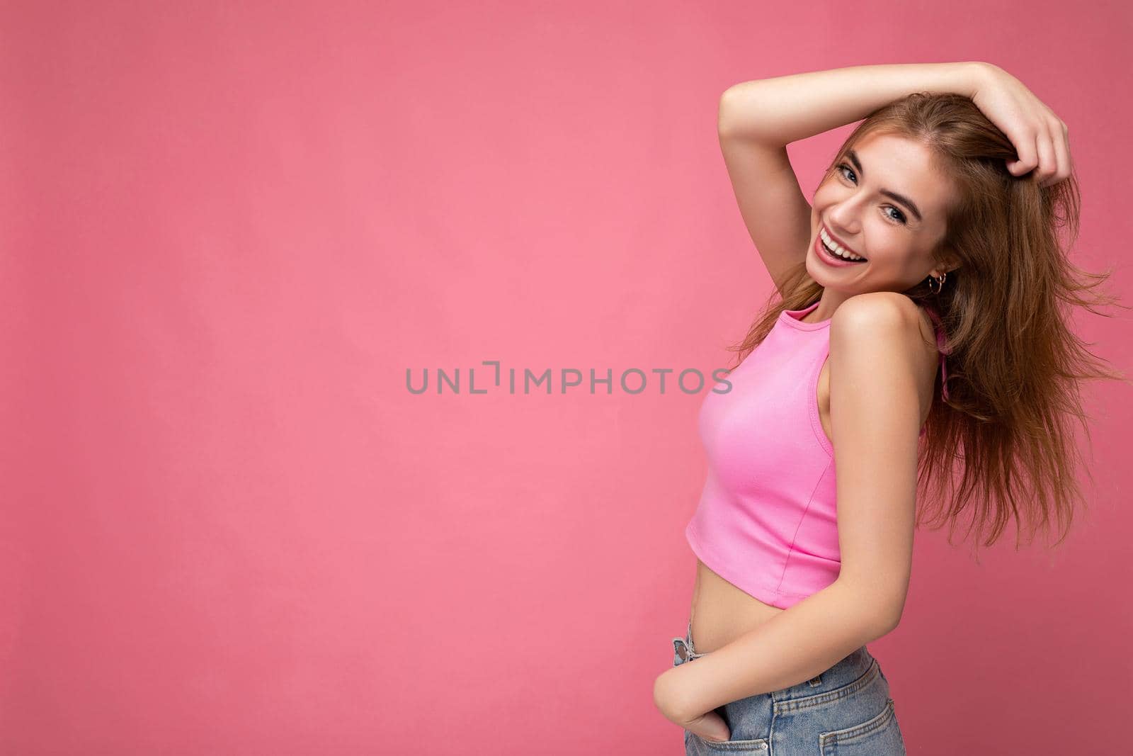 Photo of beautiful positive smiling adult woman wearing stylish clothes standing isolated on colorful background with copy space looking at camera.
