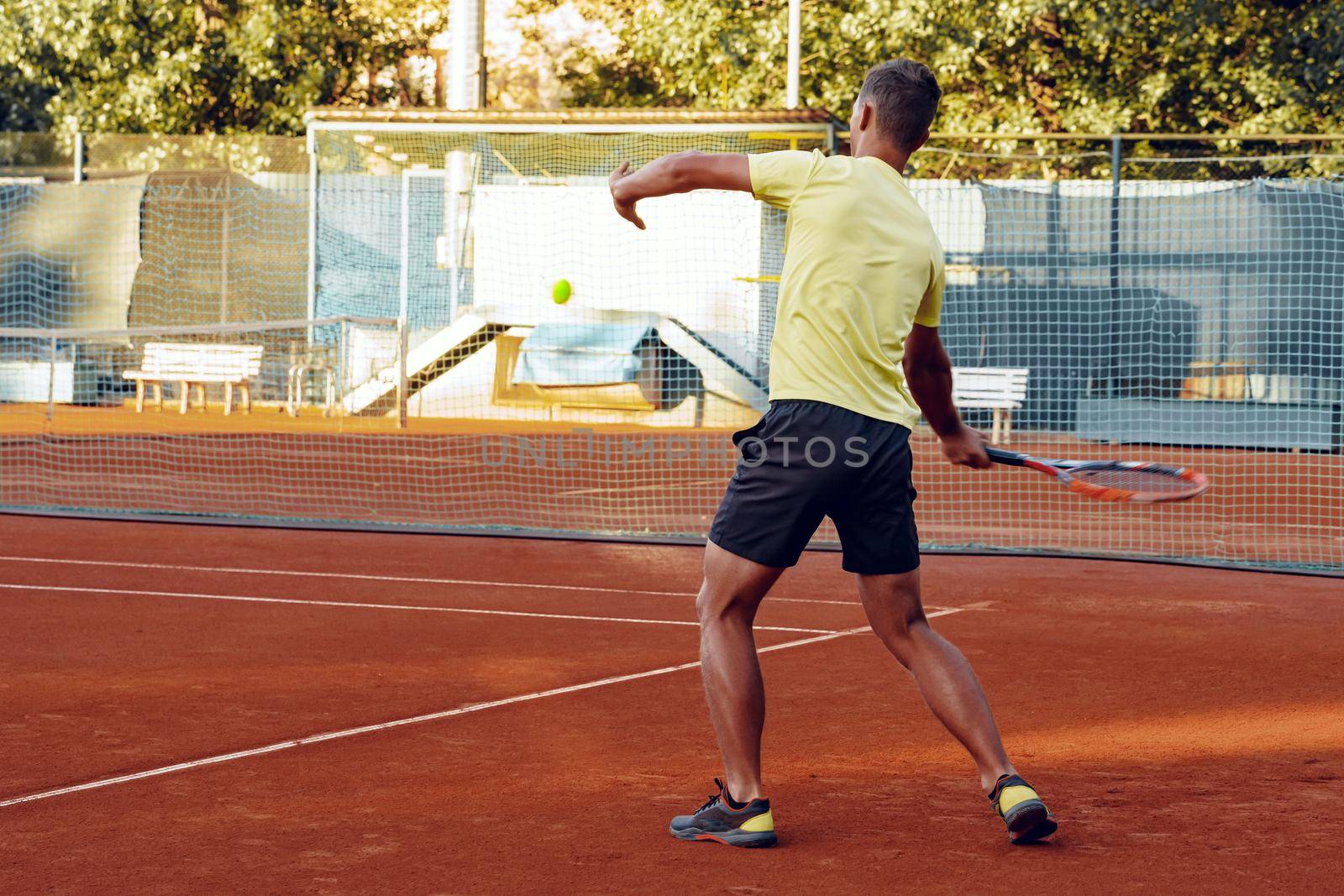 Back view photo of a man playing tennis on tennis court