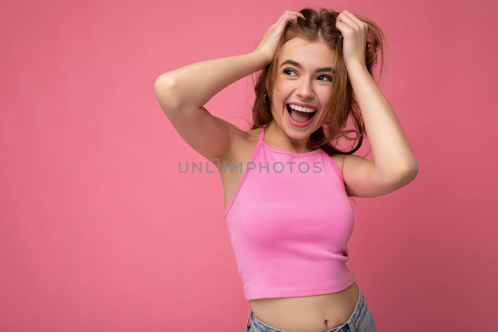 Shot of attractive happy smiling young woman wearing casual outfit standing isolated over colourful background with empty space looking to the side.