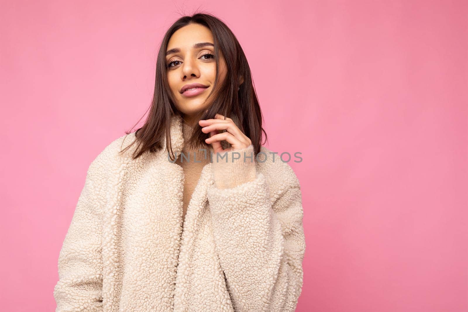 Portrait of attractive self-confident positive happy good-looking stylish young brunette woman wearing autumn beaige warm coat isolated on pink background with free space. Fashion concept.