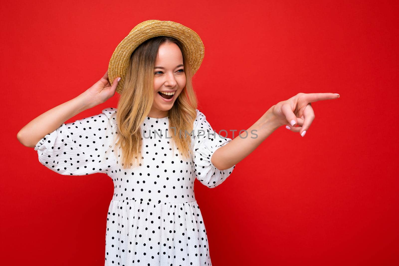 Portrait of beautiful fascinating emotional positive joyful happpy female promoter pointing to the side at copy space for advertising wearing hipster outfit isolated over background wall with empty space with sincere emotions. Summer concept.