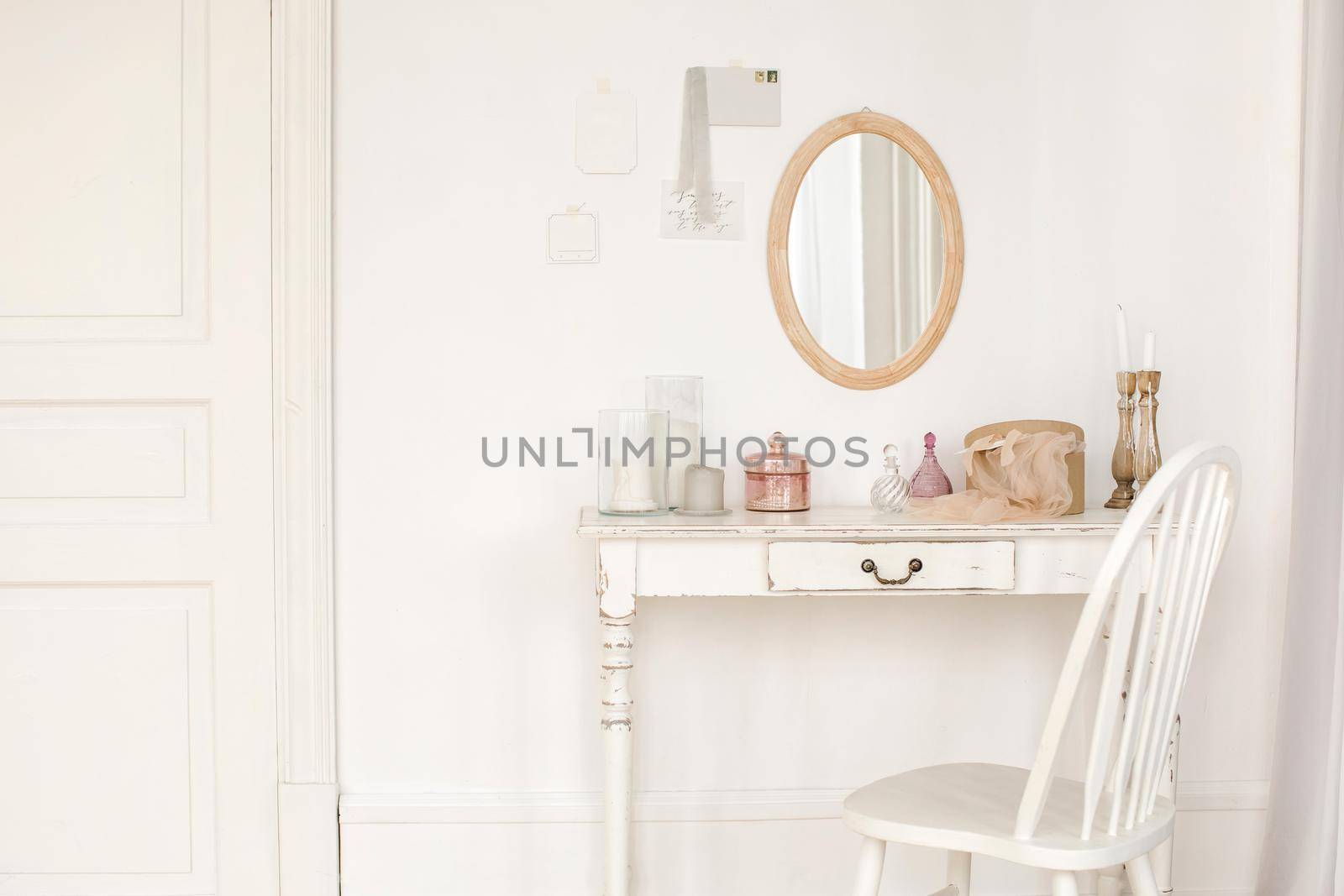 White colored vintage table and chair and mirror hanging on the wall in room