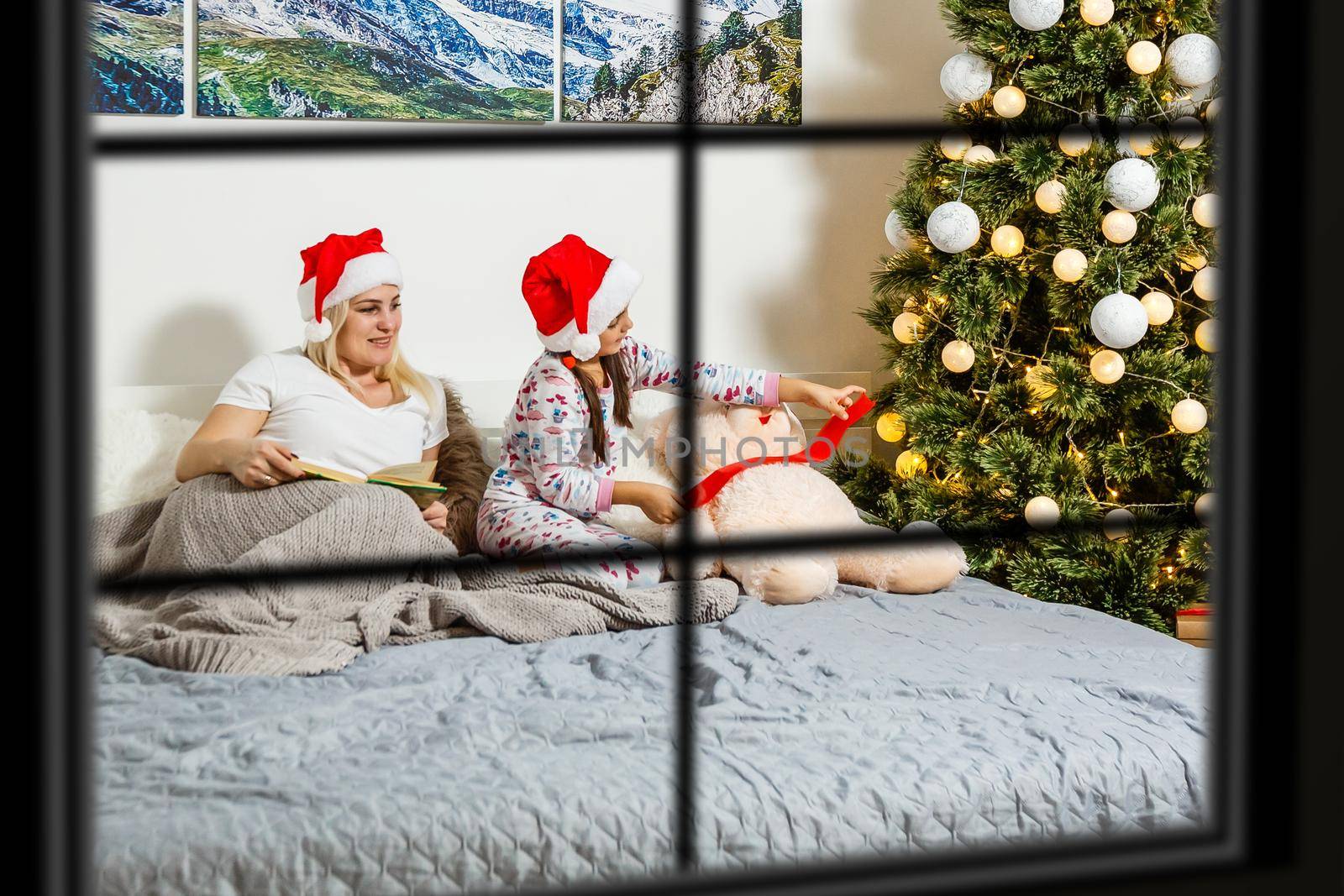 Big family with three children celebrating Christmas at home. Festive dinner at fireplace and Xmas tree. Parent and kids eating at fire place in decorated room. Child lighting advent wreath candle