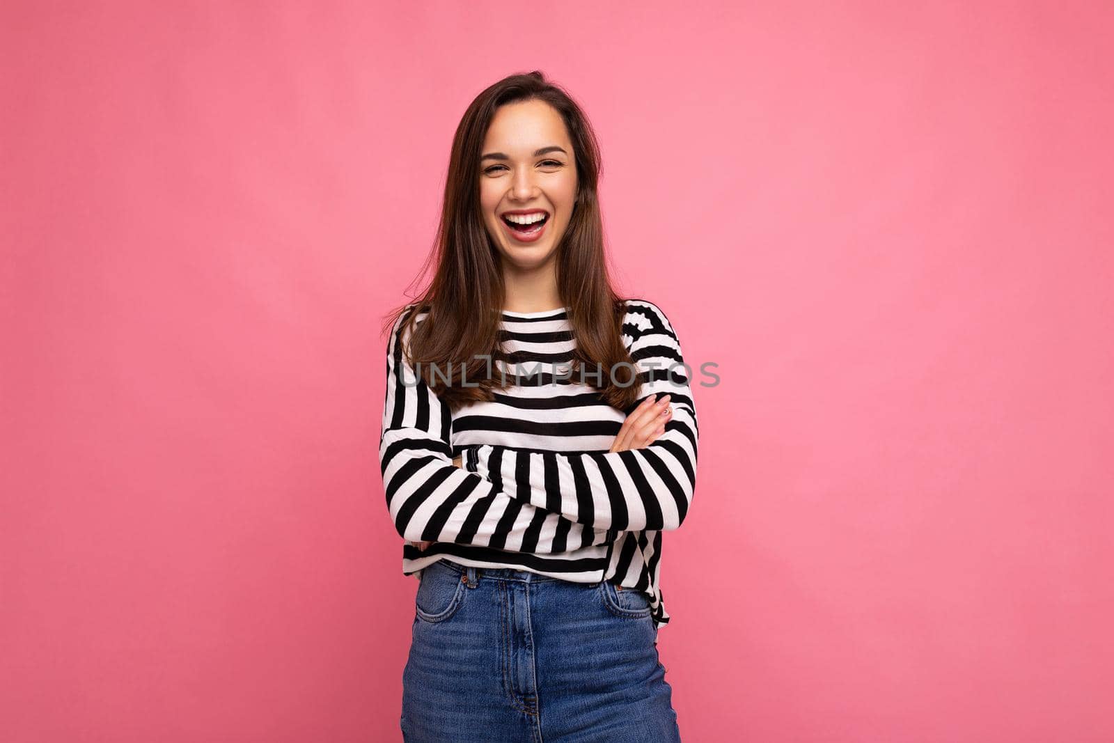 Photo portrait of young beautiful smiling hipster brunette woman in trendy pullover. Sexy carefree female person posing isolated near pink wall with empty space in studio. Positive model with natural makeup by TRMK
