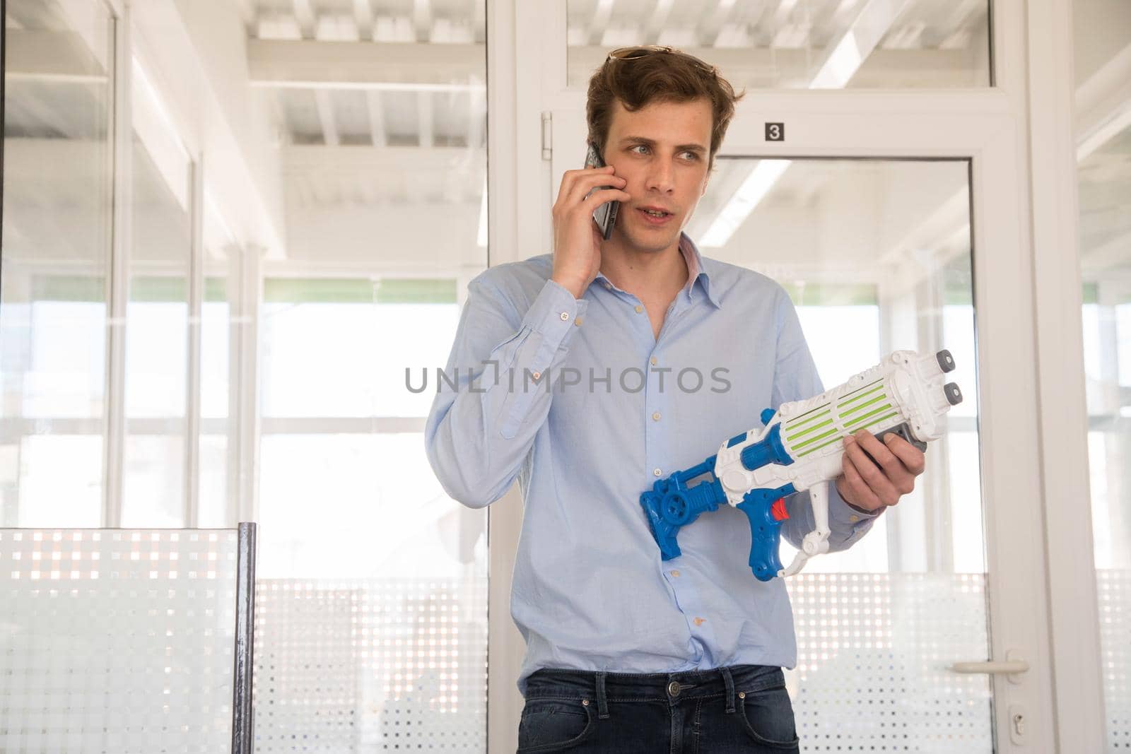 Low angle of busy male worker standing with toy and having conversation on mobile phone in office