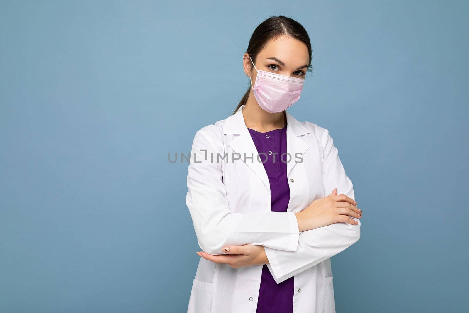 Young woman wearing an anti virus protection mask to prevent others from corona COVID-19 and SARS cov 2 infection isolated over blue background.