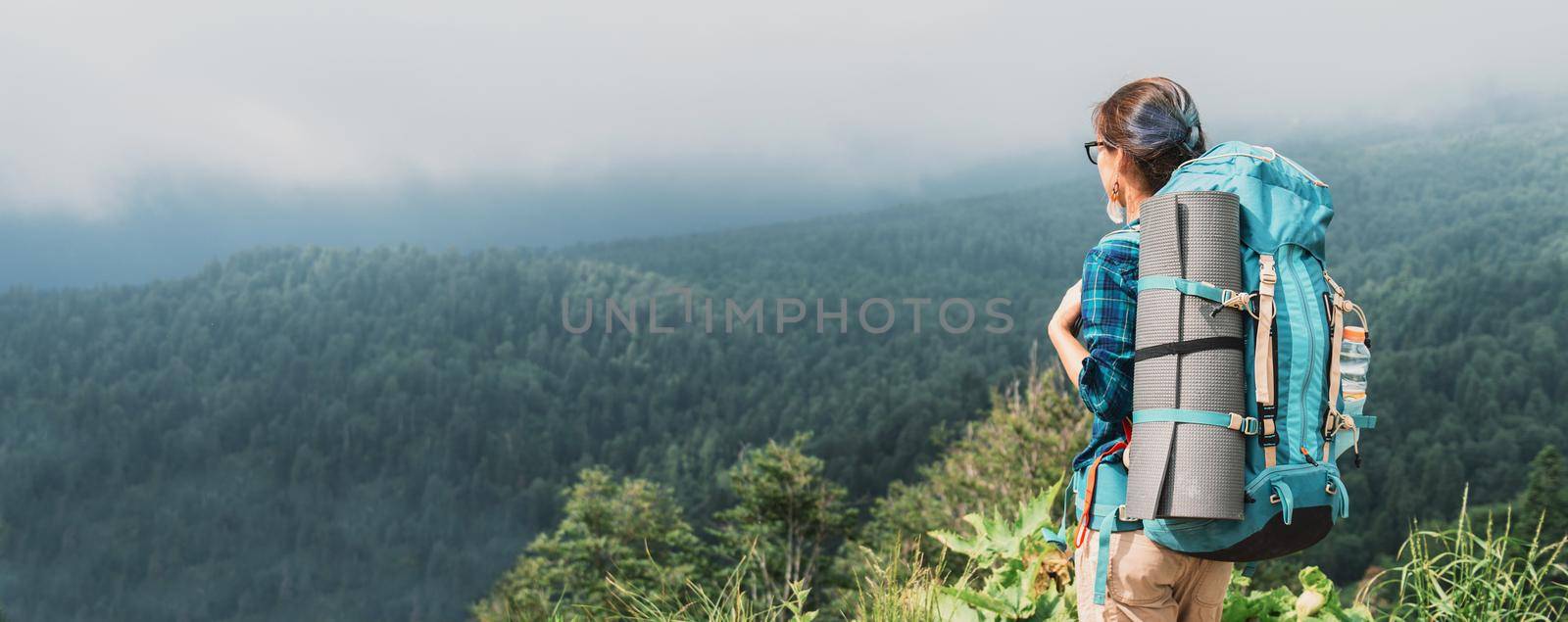 Explorer young woman with backpack looking at the mountains in summer