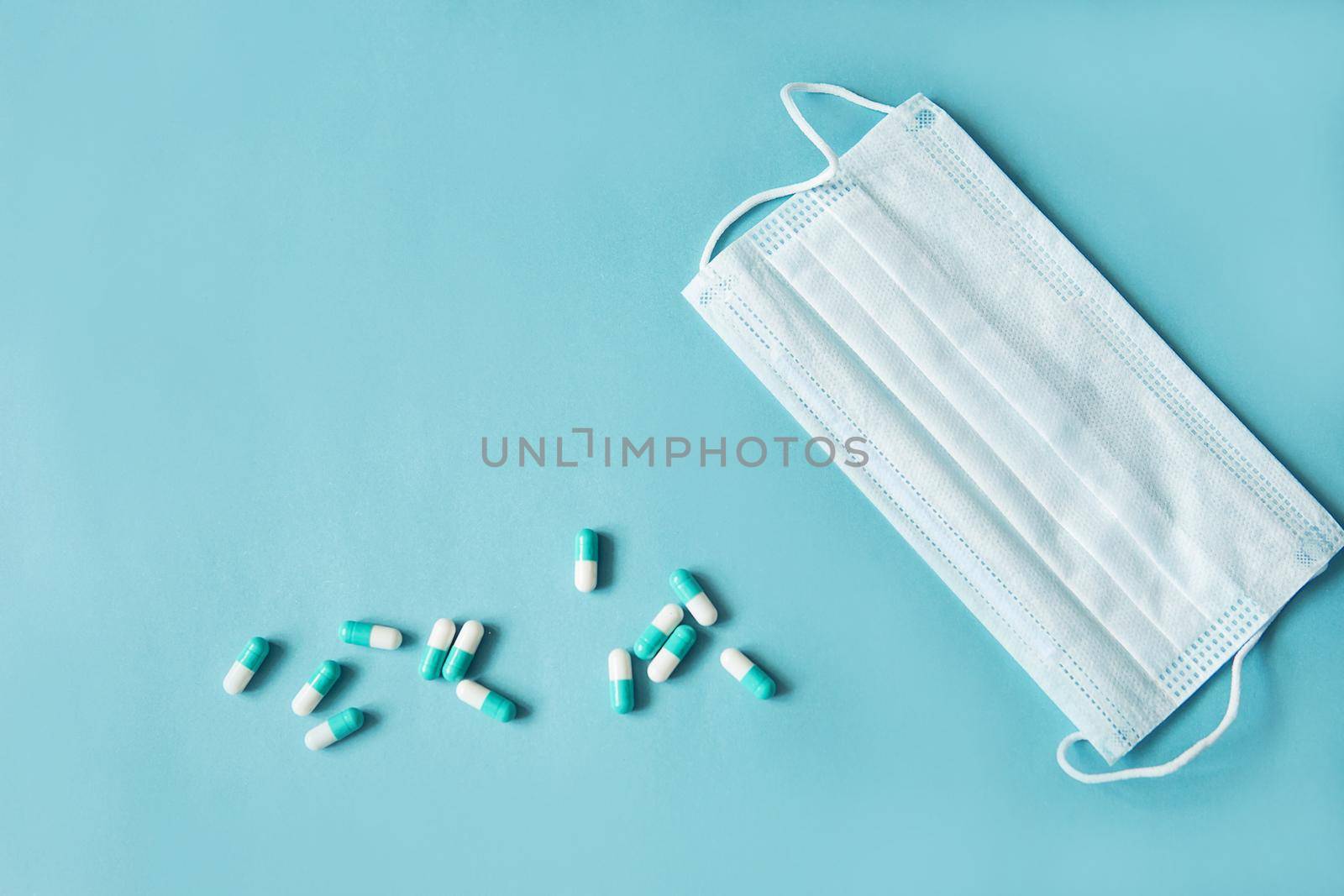 Respiratory mask and medicine in capsules on blue background.Virus prevention and treatment.