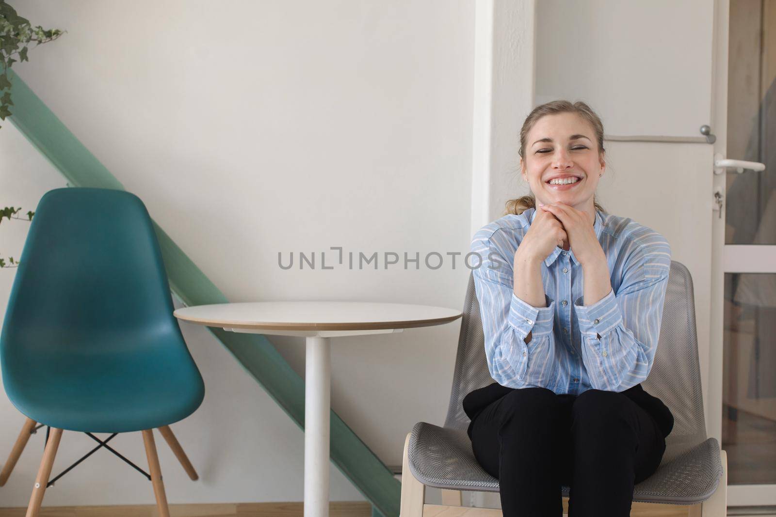 Crop view of attractive female with close eyes sitting on chair and smiling