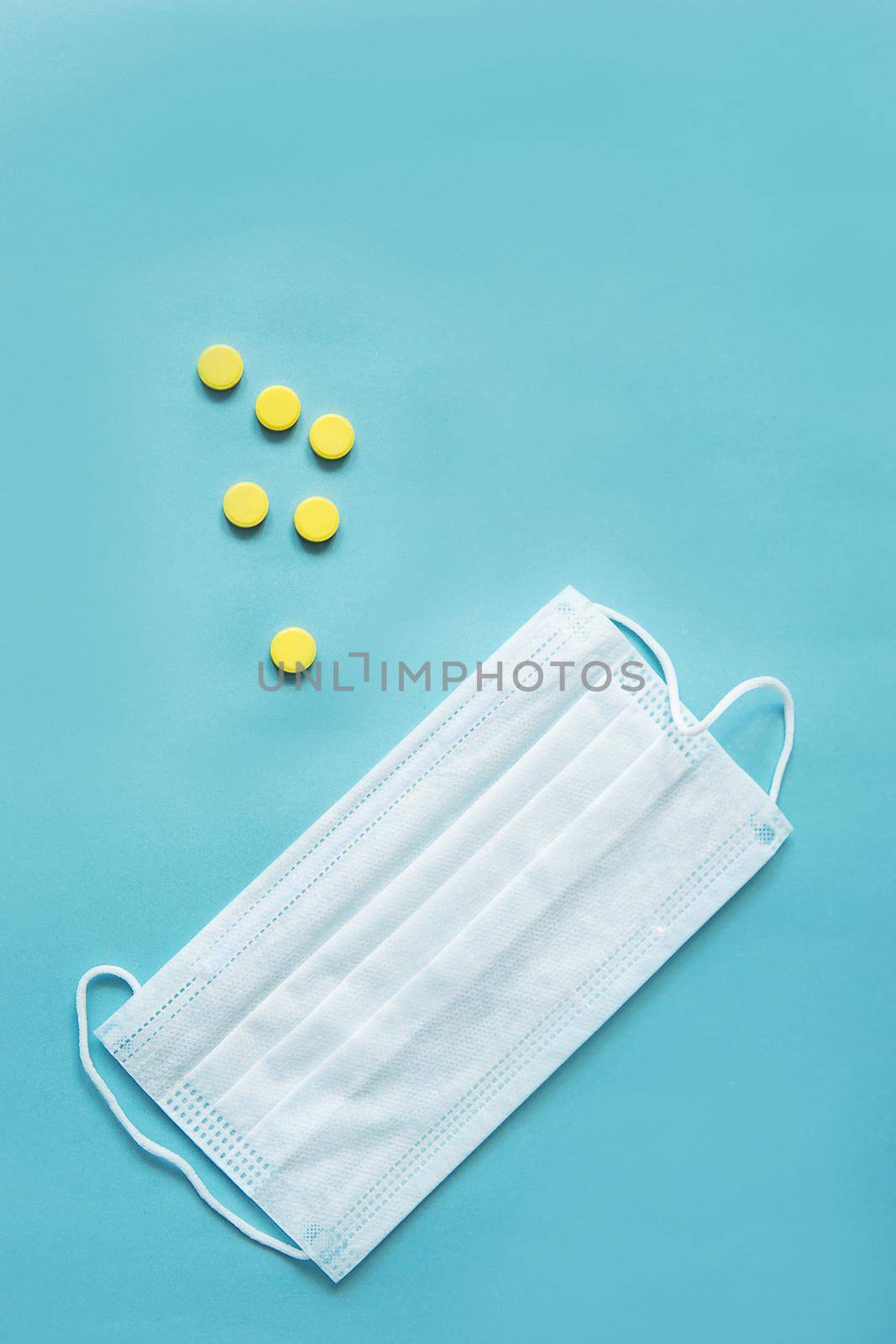 Respiratory mask and medicine in capsules on blue background.Virus prevention and treatment.