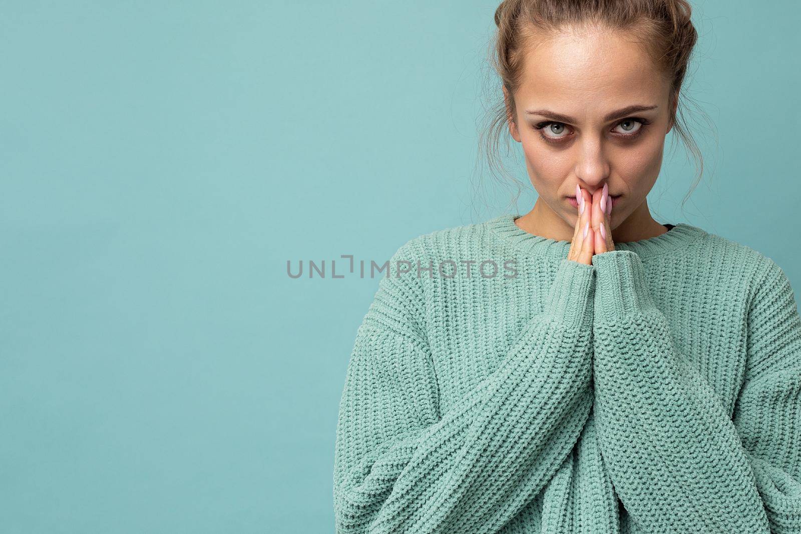 Closeup photo of young positive beautiful blonde woman with sincere emotions wearing casual blue pullover isolated over blue background with copy space and doing namaste gesture. Yoga concept by TRMK