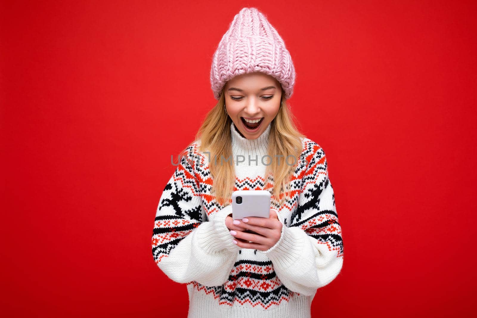 Photo of attractive crazy amazed surprised young woman wearing casual stylish clothes standing isolated over background with copy space holding and using mobile phone looking at device display.