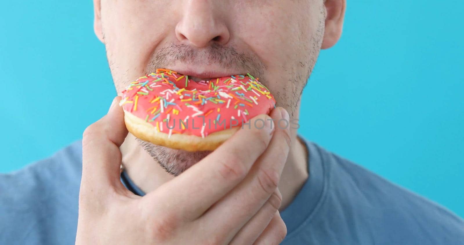 Man eat donut closeup on a blue background by Demkat
