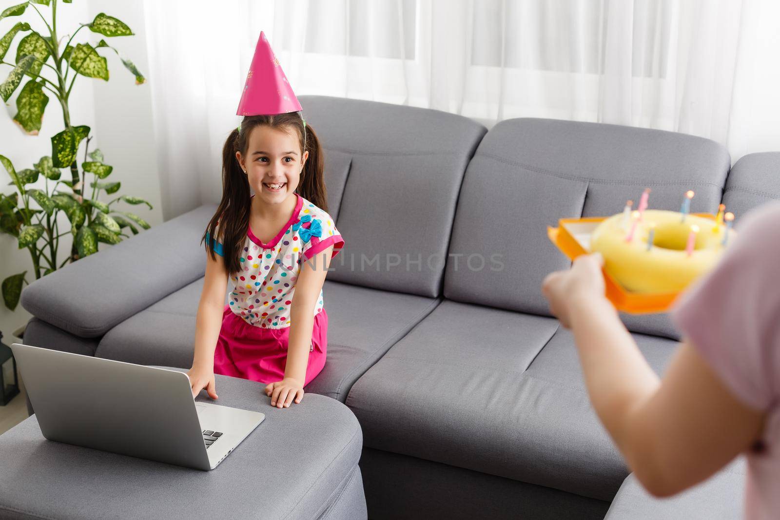 Happy girl sibling celebrating birthday via internet in quarantine time, self-isolation and family values, online birthday party. Congratulations animator via laptop, online. Stay at home