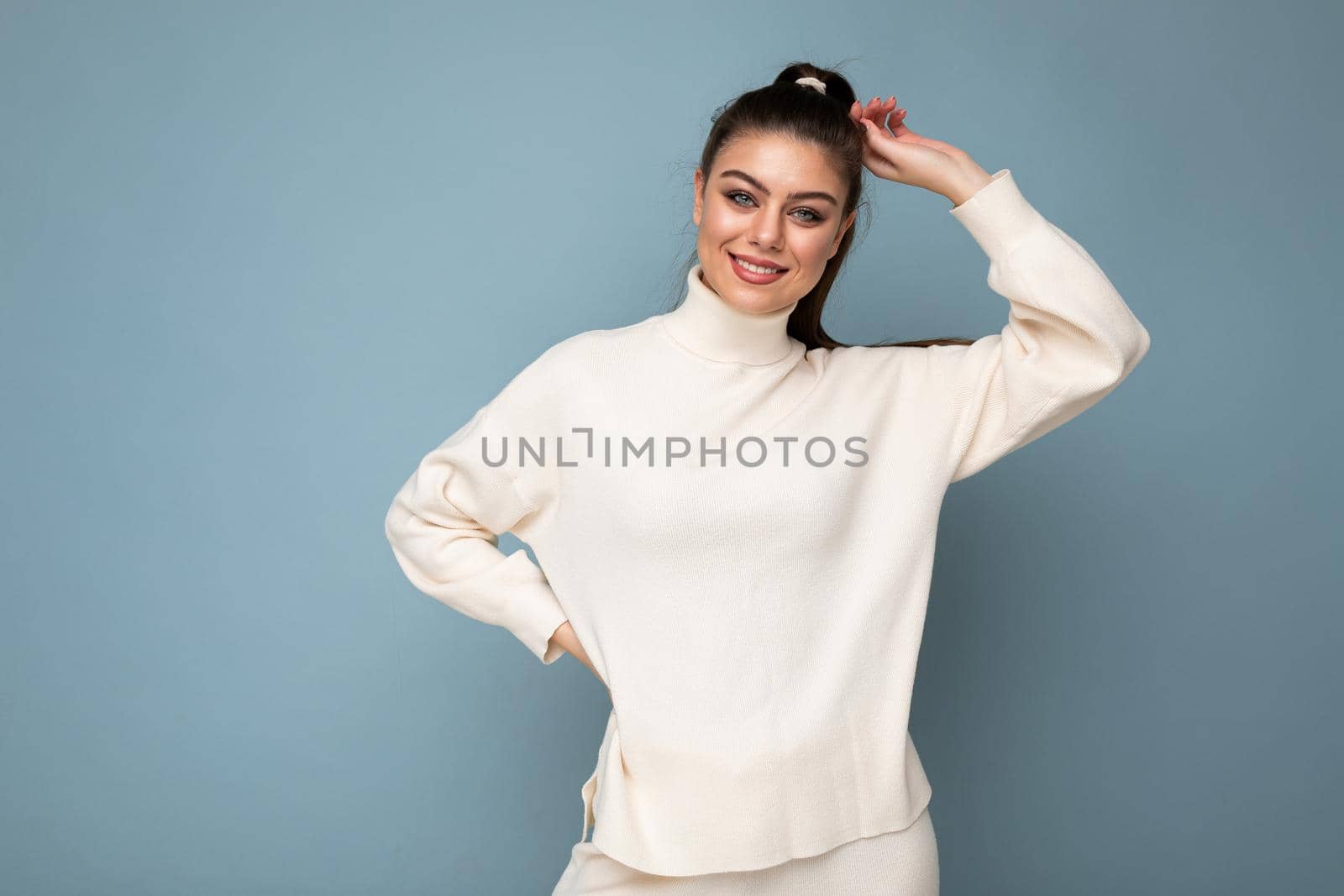 Lovely young woman wearing warm sweater standing isolated over blue background, posing. Joy and fun concept.