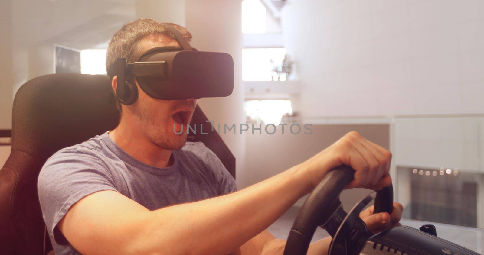 Computer simulation. Man in vr glasses racing steering wheel by Demkat