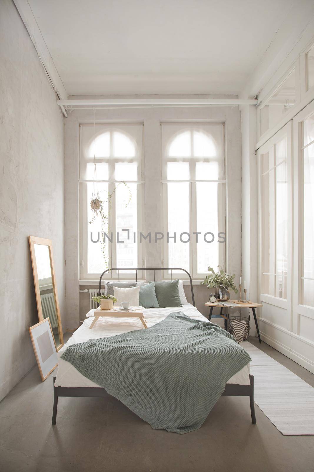 Interior of white and gray cozy bedroom near to white desk with plant