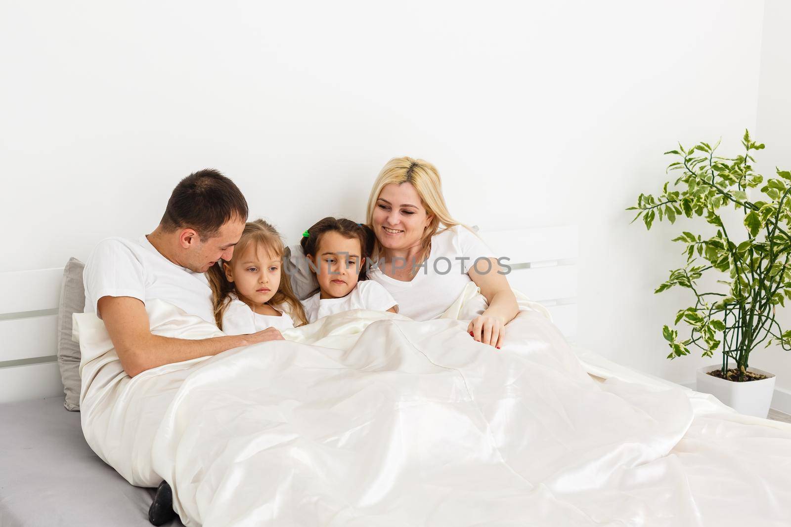 Young family resting together in parent's bed.