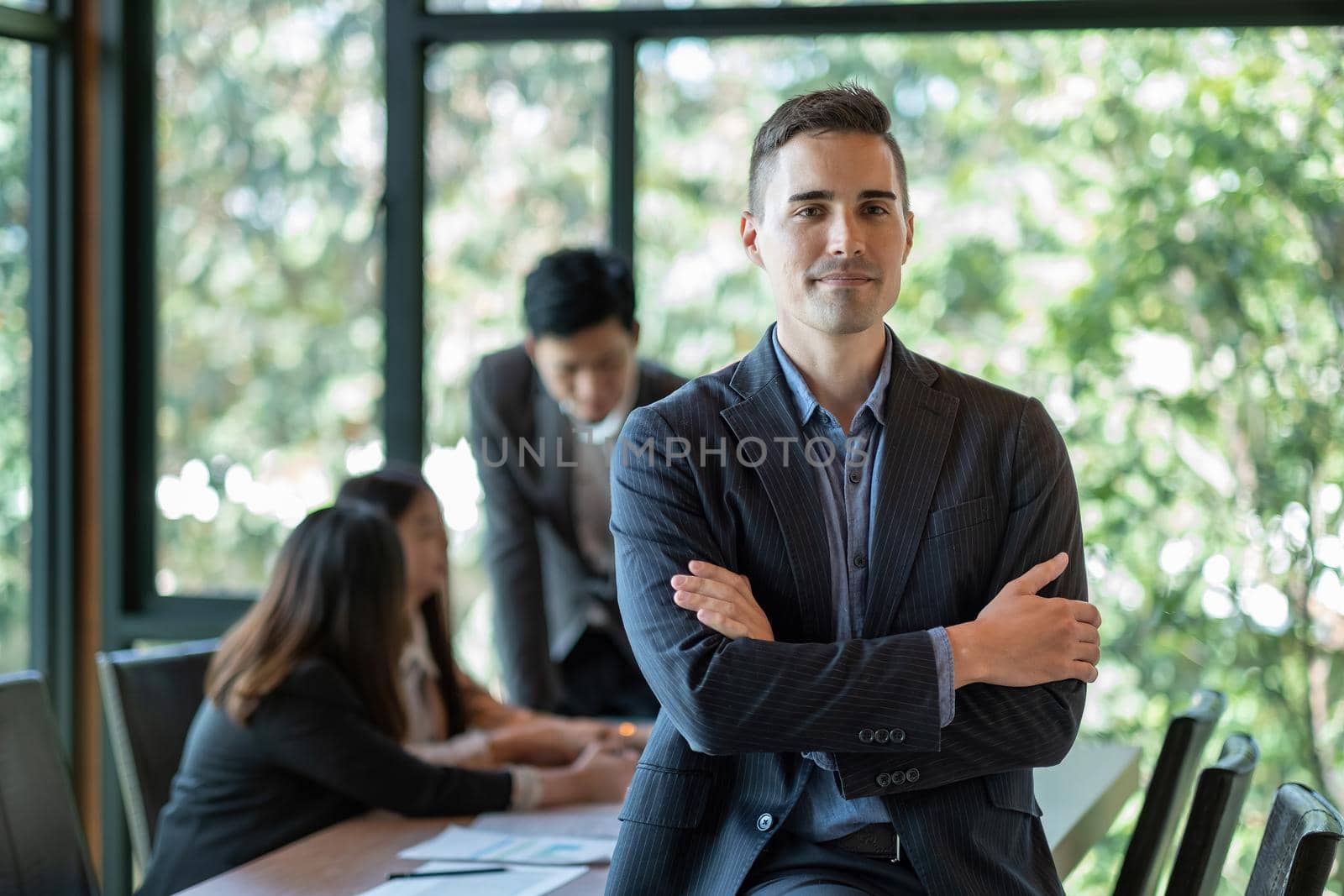 Portrait of a smiling handsome businessman with crossed arms in a meeting room.