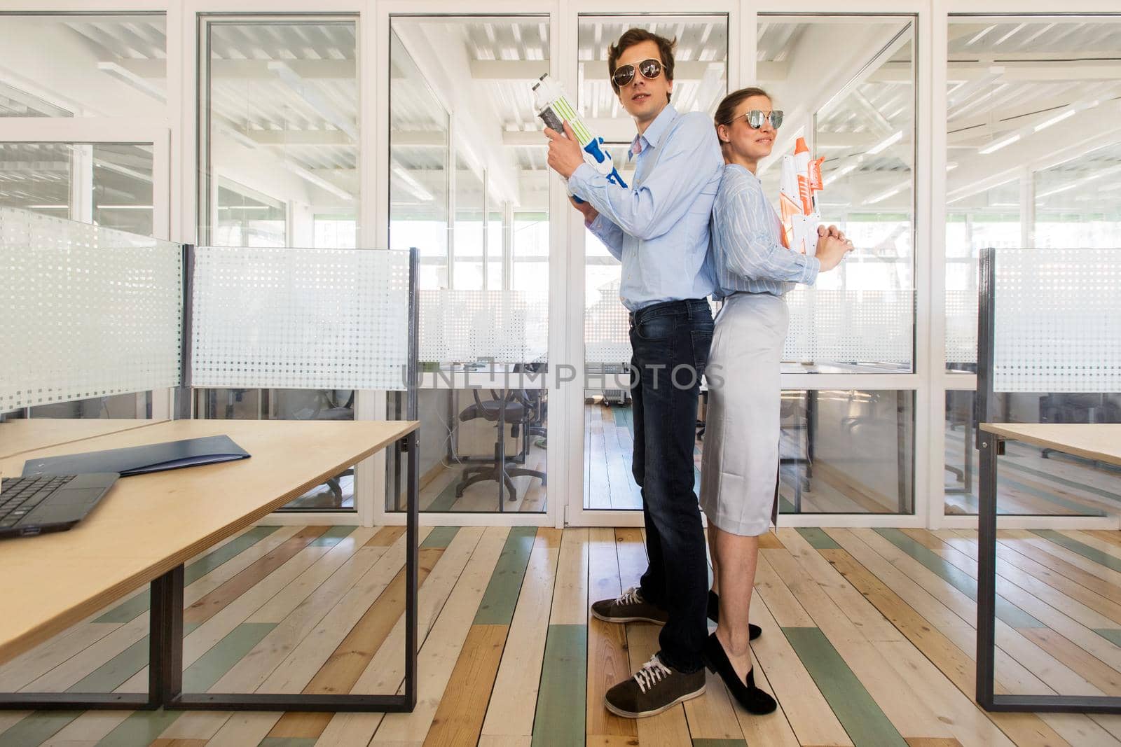 Laughing coworkers with toy guns in office by Demkat