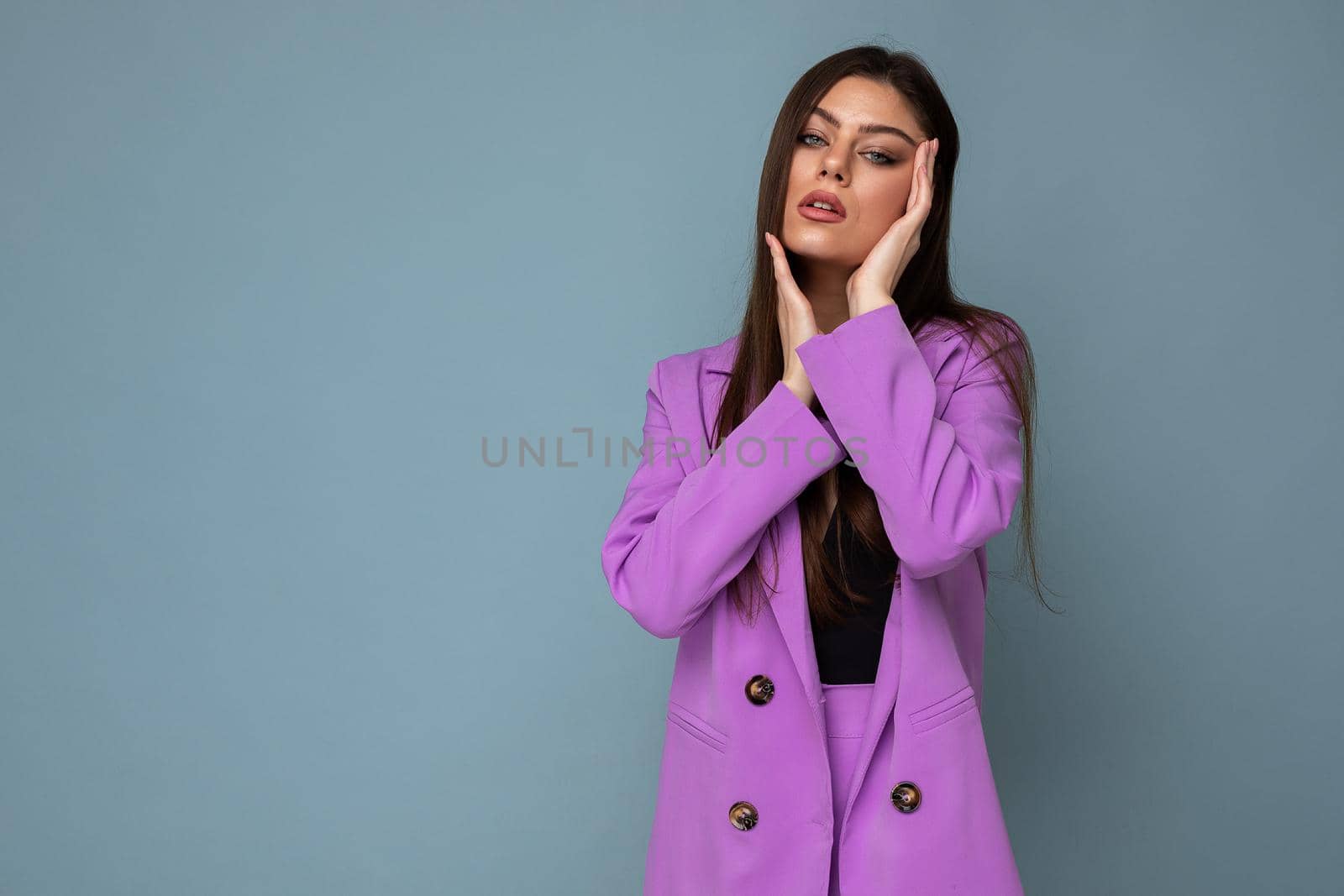 Fashion shot of young sexy happy attractive brunette woman wearing stylish violet suit isolated on blue background with empty space. Business concept.