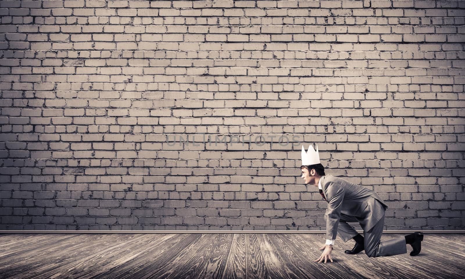 Young handsome businessman wearing white paper crown running in a hurry