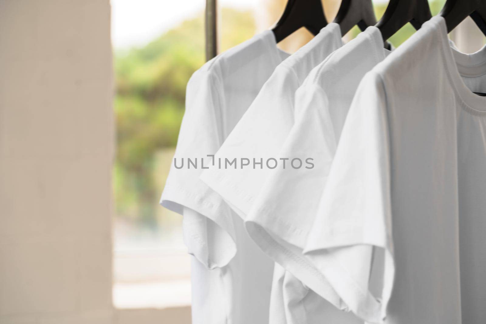 Row of white t-shirts on hangers hanging on rack
