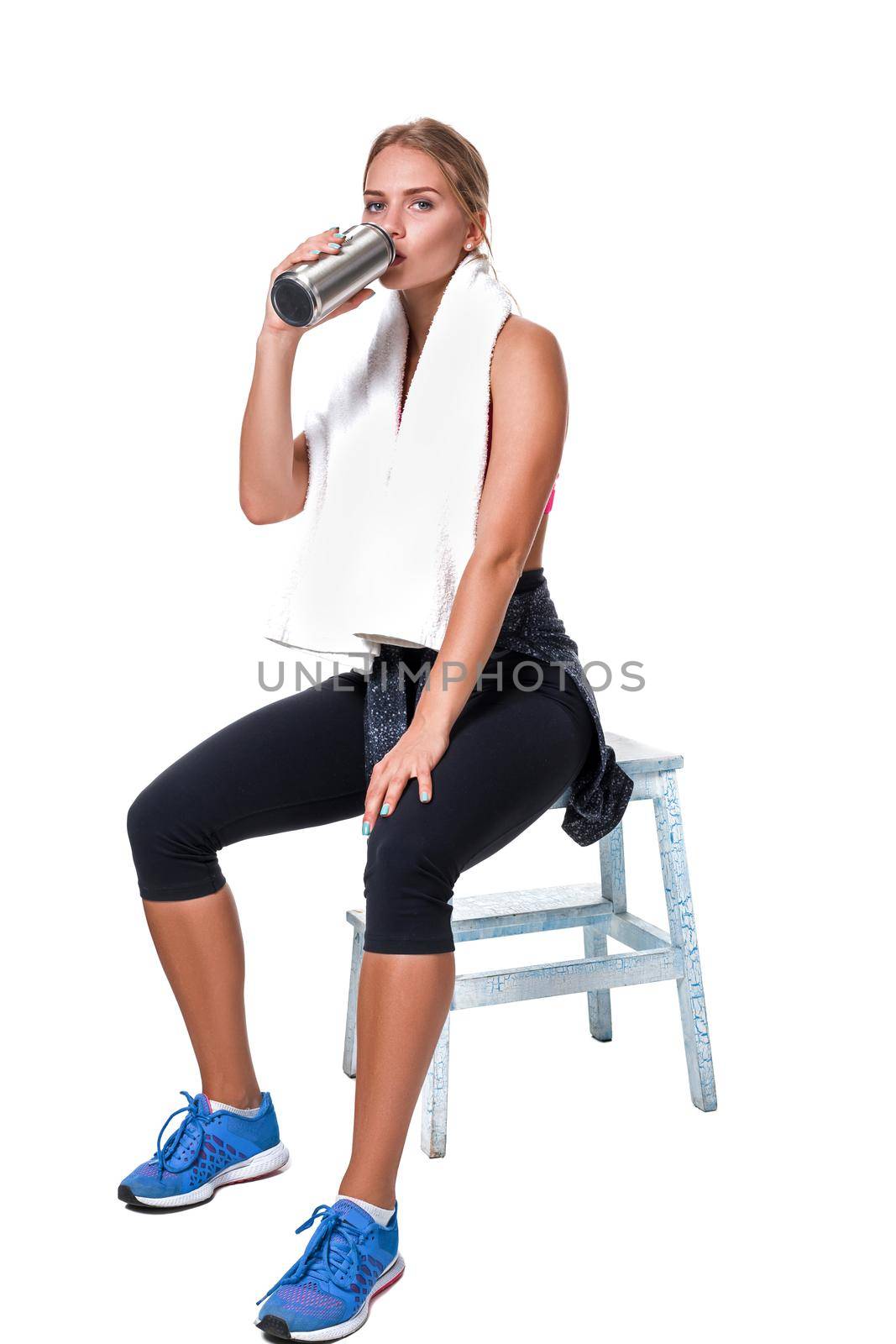 Portrait of sporty young woman tired after a gym workout. Woman with a white towel and a bottle of water isolated on white background