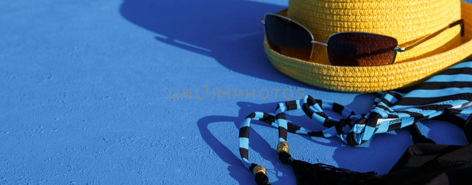 Women's accessories for a beach holiday on a blue background. The concept of a trip to the sea, relaxation, swimming, UV protection, tanning. Tourism and travel agency. Place for text. Frame. Flatlay