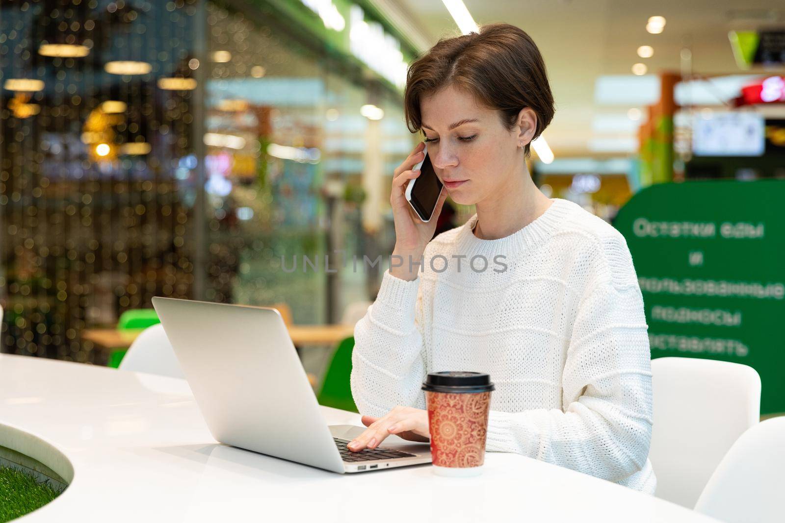 student working at a laptop in a cafe in a shopping center, concept of freelancing and remote work.
