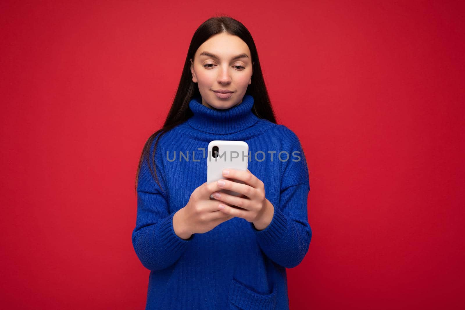 Beautiful young woman wearing casual clothes standing isolated over background surfing on the internet via phone looking at mobile screen.