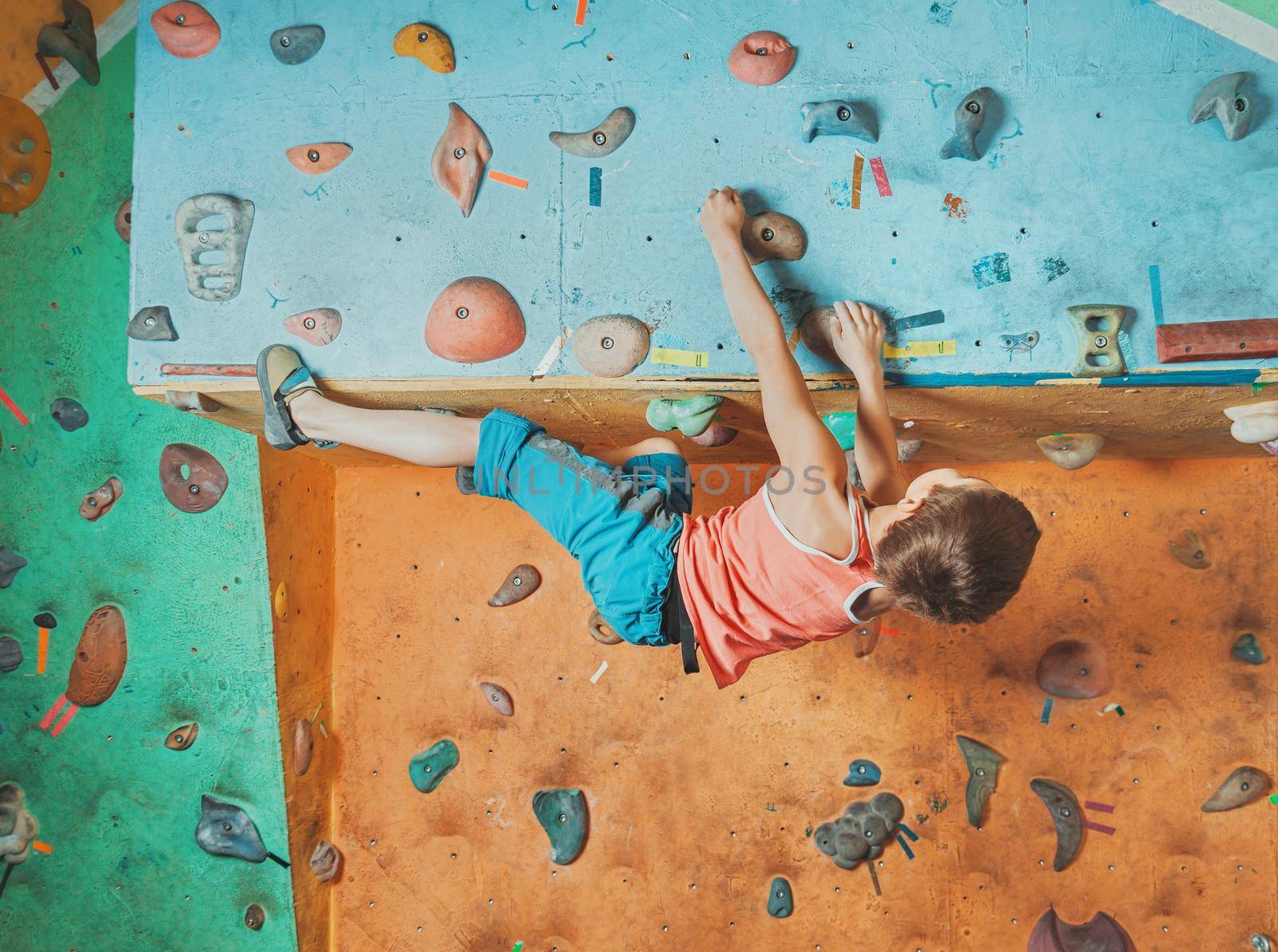 Boy practicing in climbing gym by alexAleksei