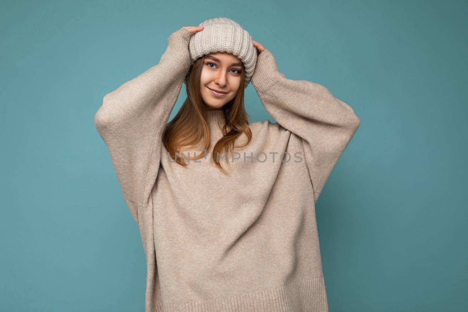 Attractive smiling happy young brunet woman standing isolated over colorful background wall wearing everyday stylish outfit showing facial emotions looking at camera.