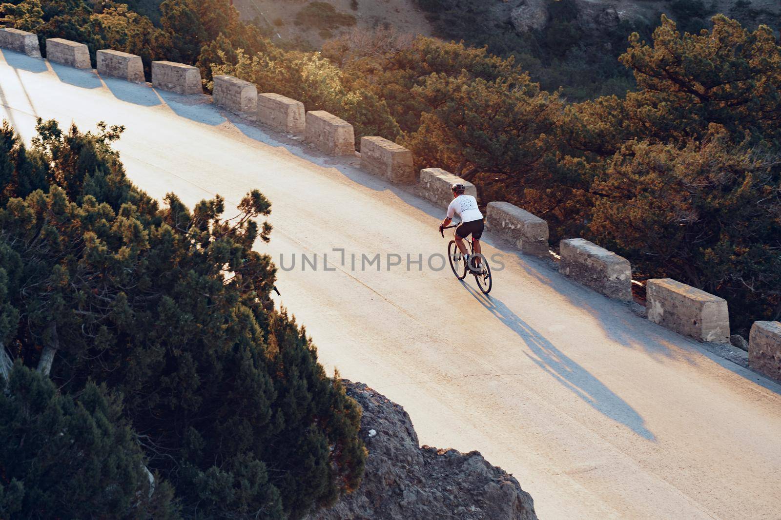 Professional man cyclist on a mountain road at sunrise