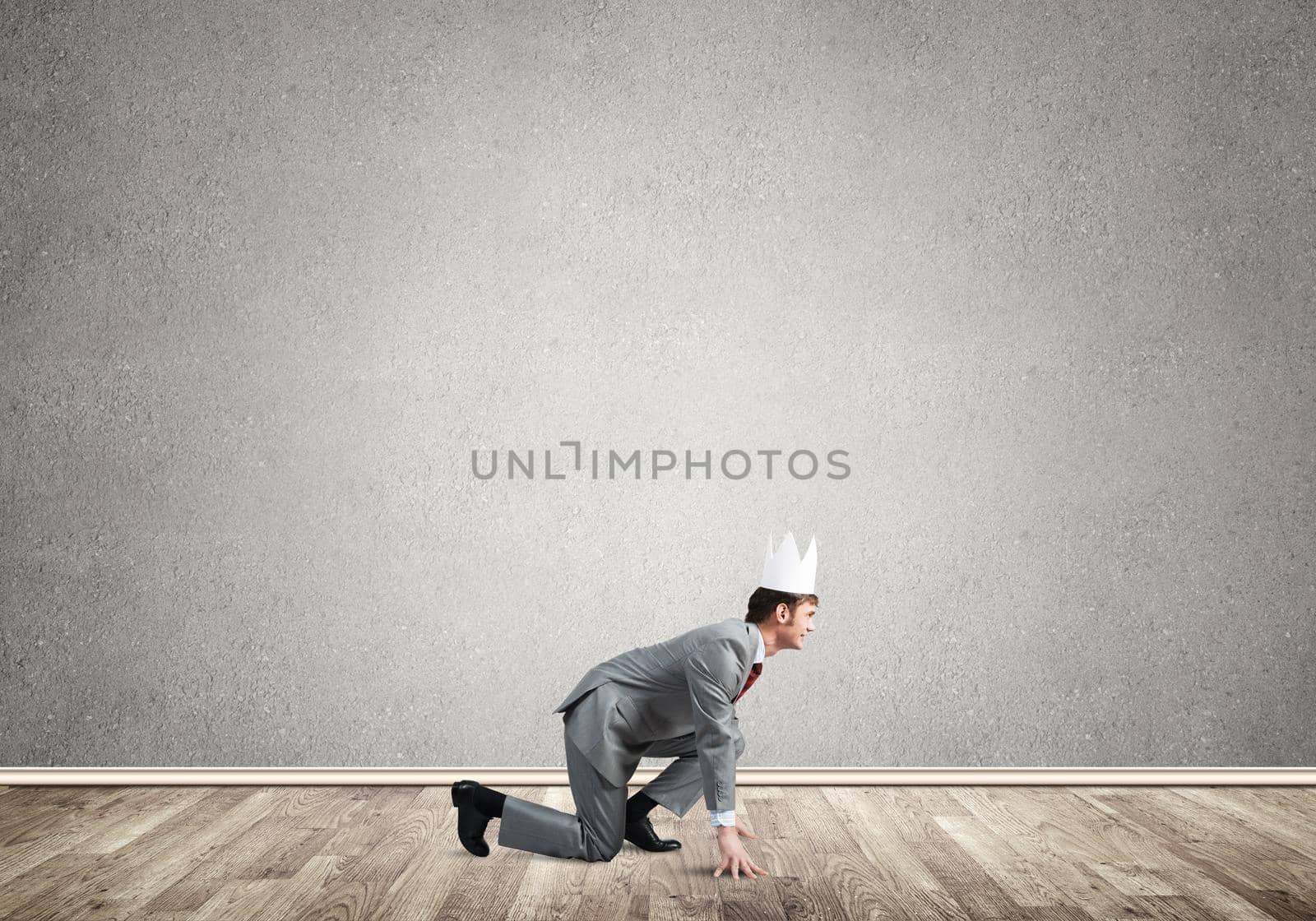 Young handsome businessman wearing white paper crown running in a hurry