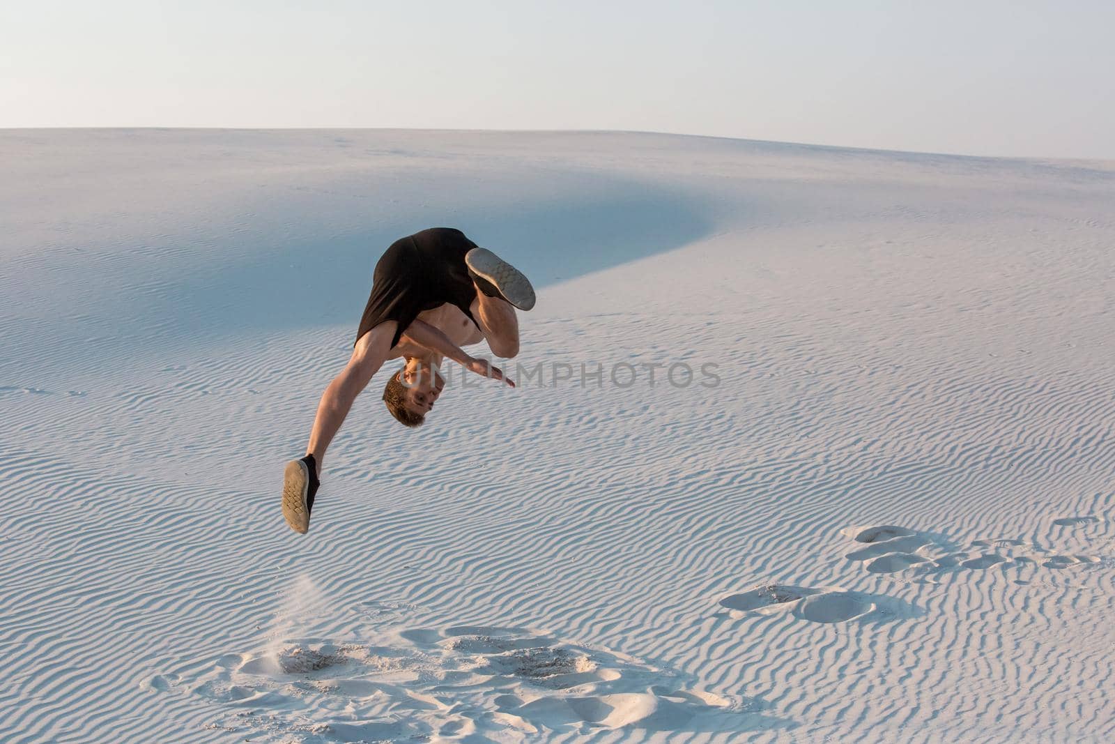 Man study parkour on their own. Acrobatics in the sand. Flip on the sand